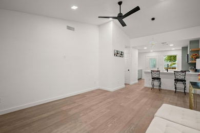Living area with ceiling fan, light wood-style fl