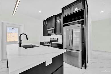 Kitchen featuring dark cabinetry, appliances with stainless steel finishes, marble finish floor, and a sink