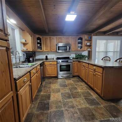 Kitchen with open shelves, glass insert cabinets, beamed ceiling, appliances with stainless steel finishes, and a peninsula