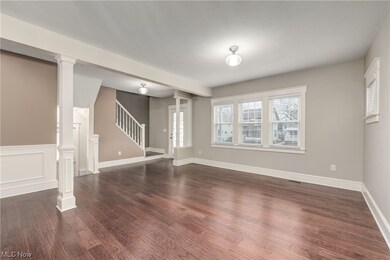 Living room featuring beam ceiling, dark hardwood flooring, and a wealth of natural light.