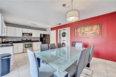 Dining area featuring stacked washer and clothes dryer, light tile patterned floors, and a textured wall