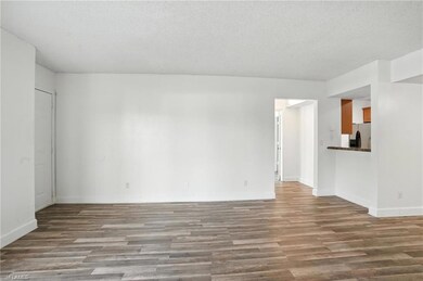 Unfurnished living room with wood finished floors and a textured ceiling