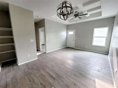Unfurnished living room with ceiling fan with notable chandelier, baseboards, coffered ceiling, and wood finished floors