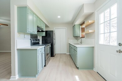 Kitchen with green cabinetry, a sink, light counte