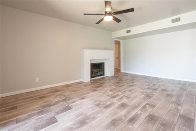 Unfurnished living room featuring a fireplace, light wood finished floors, and ceiling fan