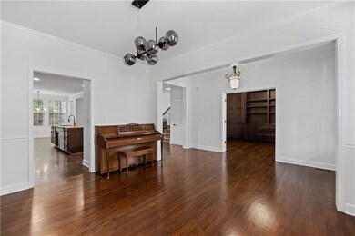 Dining space with crown molding, dark wood-type flooring, a chandelier, and stairway