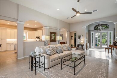 Living area featuring arched walkways, french doors, ornate columns, recessed lighting, and a chandelier