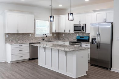Kitchen featuring stainless steel appliances, white cabinetry, backsplash, and recessed lighting