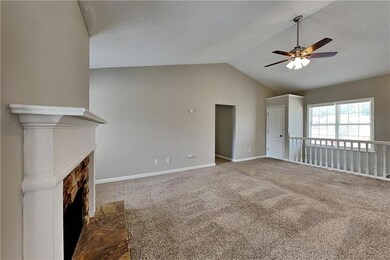 Unfurnished living room featuring a fireplace, dark colored carpet, vaulted ceiling, a textured ceiling, and ceiling fan