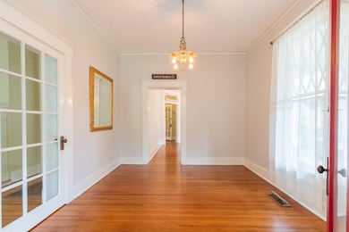 Unfurnished dining area with french doors, plenty of natural light, wood finished floors, a chandelier, and ornamental molding