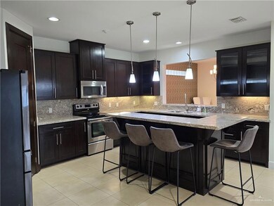Kitchen featuring stainless steel appliances, a breakfast bar, decorative backsplash, light stone countertops, and light tile patterned floors