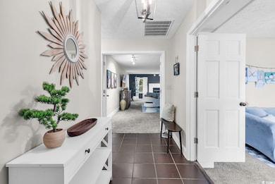 Hallway featuring dark carpet, a textured ceiling, dark tile patterned flooring, and baseboards
