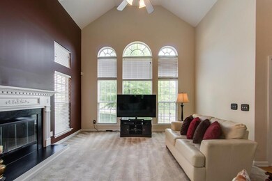 Volume ceiling, fireplace, fan and wall of windows enhance the formal living room.