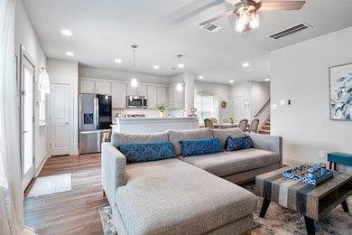 Living area featuring light wood-style flooring, a ceiling fan, recessed lighting, and stairway