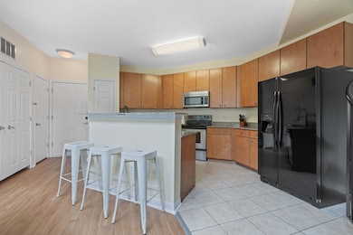Kitchen featuring appliances with stainless steel finishes, brown cabinetry, a center island, a kitchen breakfast bar, and light wood-type flooring