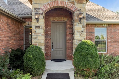 View of exterior entry featuring a shingled roof and brick siding