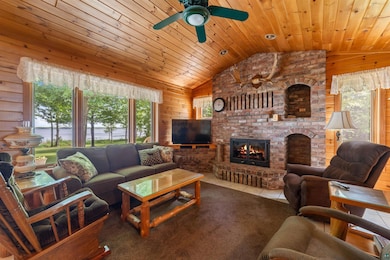 Tiled living area with lofted ceiling, wooden walls, a ceiling fan, a brick fireplace, and wood ceiling