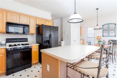 Kitchen with black appliances, a kitchen breakfast bar, pendant lighting, and light countertops