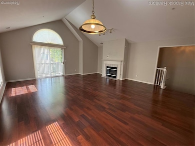 Unfurnished living room featuring dark wood-style floors, a tile fireplace, and high vaulted ceiling
