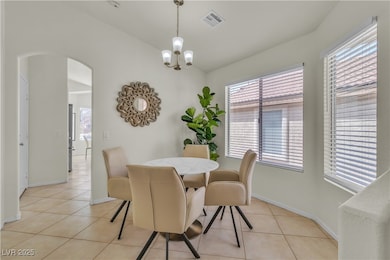 Dining room with arched walkways, light tile patterned flooring, plenty of natural light, and a chandelier