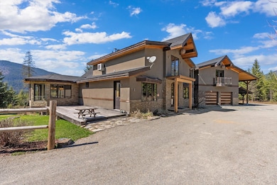 Contemporary house with an attached garage, a balcony, stone siding, and stucco siding