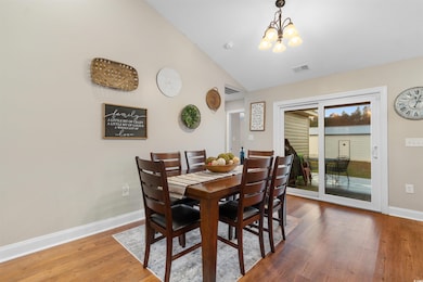 Dining space featuring light wood finished floors, vaulted ceiling, and a chandelier