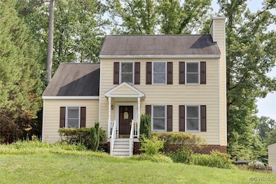Colonial-style house with a chimney, a front yard, and roof with shingles