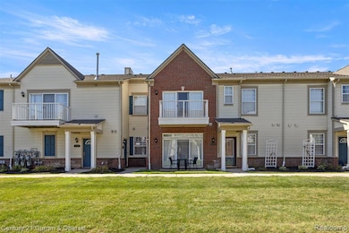 Traditional-style house featuring a balcony, a front lawn, and brick siding