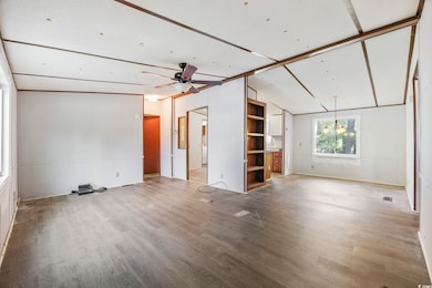 Unfurnished living room featuring wood finished floors, lofted ceiling, and a ceiling fan