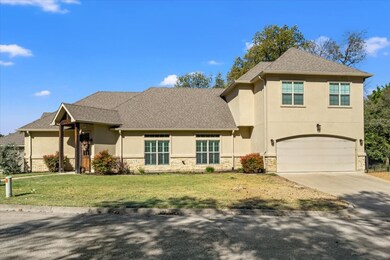 Traditional home featuring stone siding, driveway, stucco siding, a front lawn, and roof with shingles