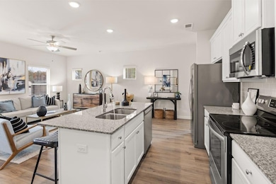 Kitchen featuring stainless steel appliances, recessed lighting, light wood finished floors, white cabinetry, and a kitchen breakfast bar