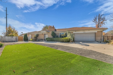 Ranch-style house featuring driveway, a chimney, brick siding, and an attached garage