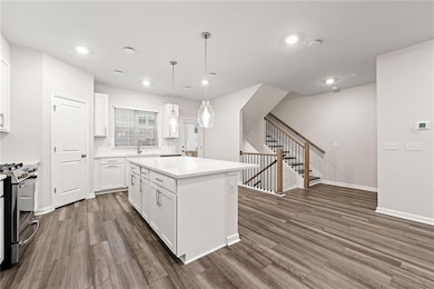 Kitchen featuring white cabinets, hanging light fixtures, gas range, dark hardwood / wood-style floors, and a center island