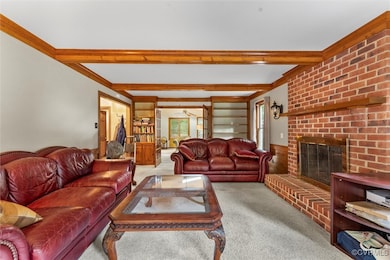 Living area featuring carpet, beam ceiling, and a