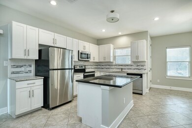Kitchen with appliances with stainless steel finishes, white cabinets, decorative backsplash, a center island, and recessed lighting