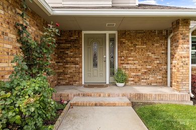 Entrance to property with covered porch and brick siding