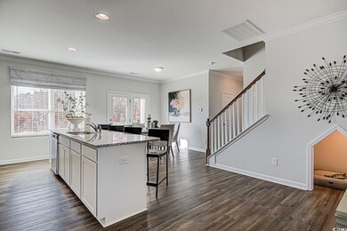 Kitchen featuring visible vents, crown molding, a center island with sink, a breakfast bar, and a sink