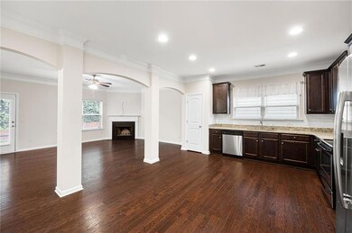 Kitchen featuring stainless steel appliances, a ceiling fan, dark brown cabinetry, a fireplace, and recessed lighting