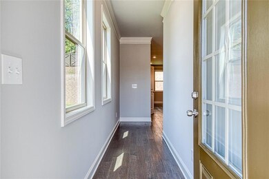 Corridor featuring dark wood finished floors, base