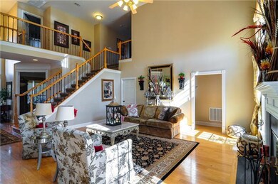 Spacious living room has soaring ceilings that open up to the upstairs and foyer