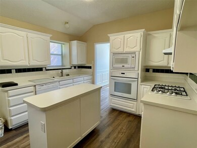 Kitchen with backsplash, white cabinetry, light countertops, lofted ceiling, and a kitchen island