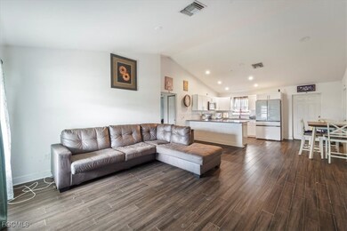 Living area with dark wood-type flooring, recessed lighting, and high vaulted ceiling