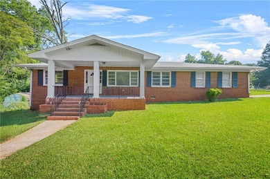 View of front of property featuring brick siding, a front lawn, and covered porch
