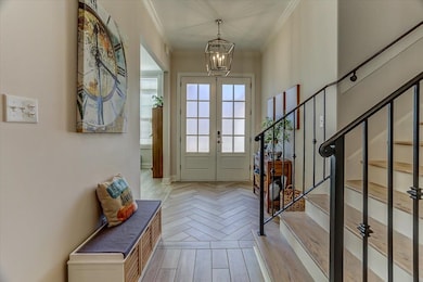 Entryway with stairway, a chandelier, crown moldin