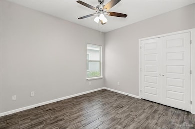 Unfurnished bedroom featuring dark wood-type flooring, a closet, ceiling fan, and baseboards