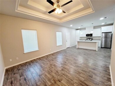 Unfurnished living room with a raised ceiling, wood finished floors, a ceiling fan, baseboards, and recessed lighting