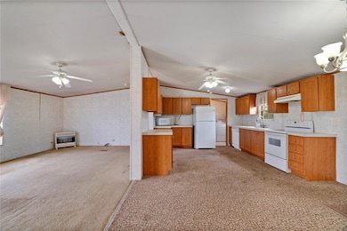 Kitchen featuring light countertops, vaulted ceiling, light carpet, white appliances, and ceiling fan