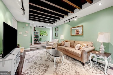 Living room featuring rail lighting, wood finished floors, baseboards, beamed ceiling, and recessed lighting