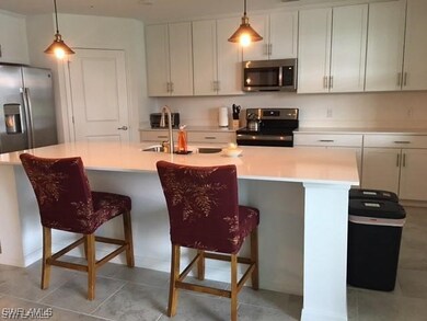 Kitchen featuring sink, appliances with stainless steel finishes, pendant lighting, and an island with sink