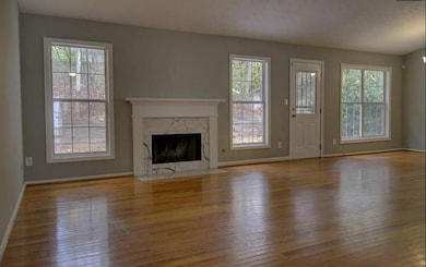 Unfurnished living room featuring baseboards, wood finished floors, and a fireplace